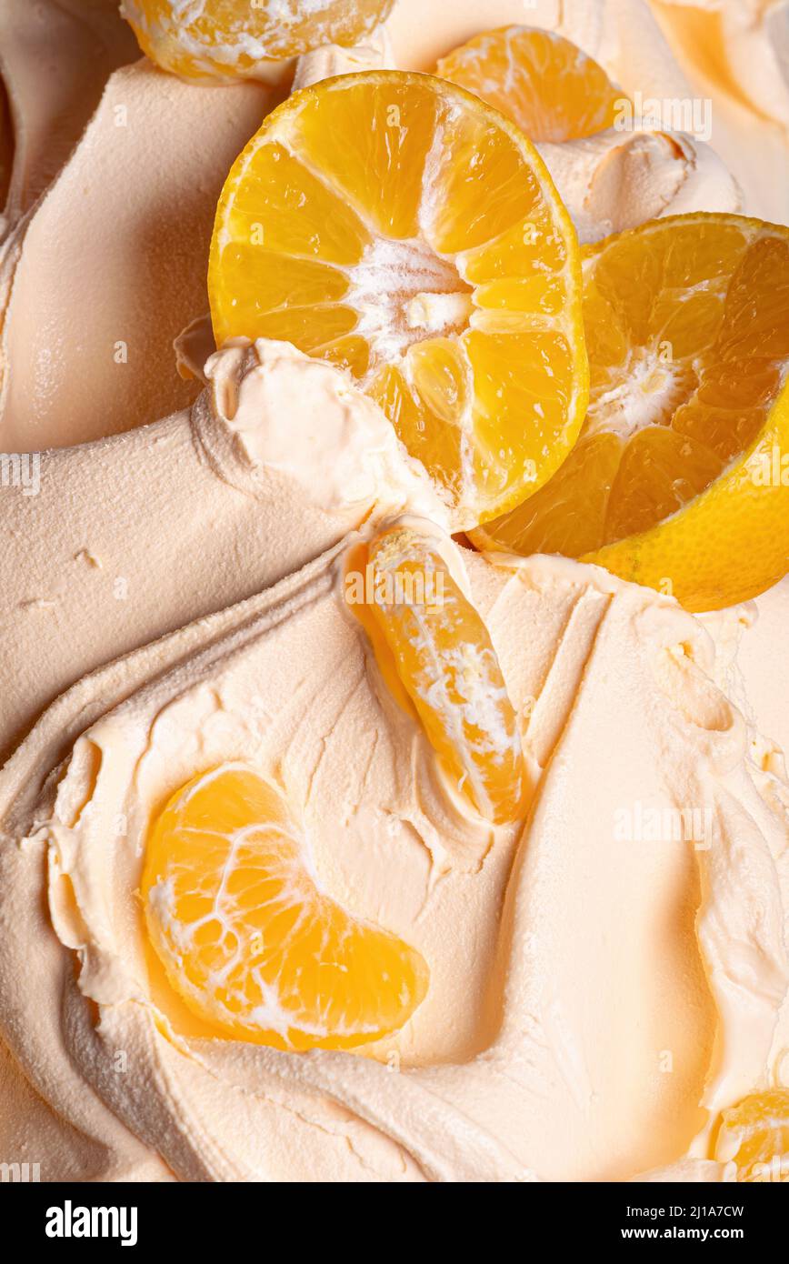 Gelato Frozen Tangerine Flavour - dettaglio telaio completo. Primo piano di una superficie di colore arancio di gelato ricoperto con pezzi di mandarino. Foto Stock