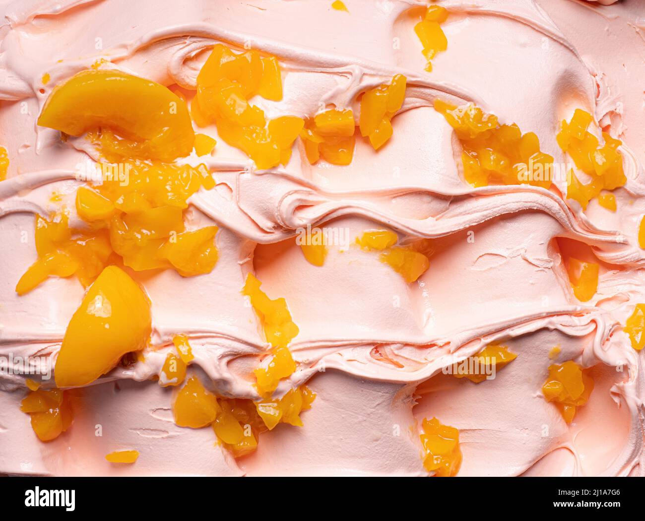 Gelato Frozen Peach Flavour - dettaglio telaio completo. Primo piano di una texture superficiale beige di gelato coperto con pezzi di frutta di colore arancio. Foto Stock