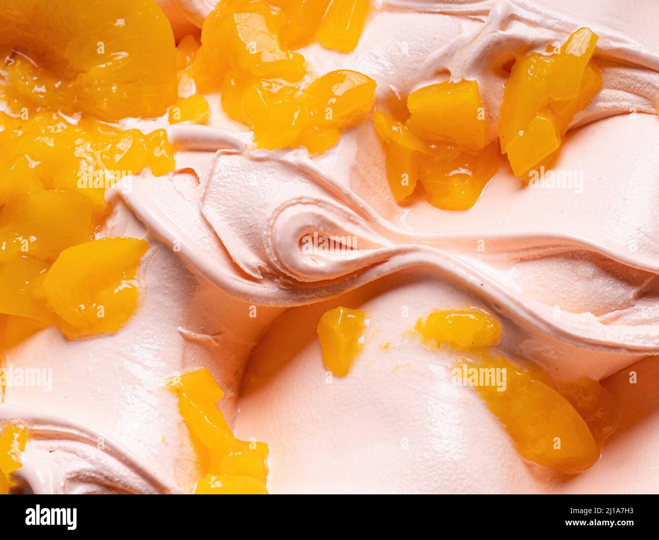 Gelato Frozen Peach Flavour - dettaglio telaio completo. Primo piano di una texture superficiale beige di gelato coperto con pezzi di frutta di colore arancio. Foto Stock