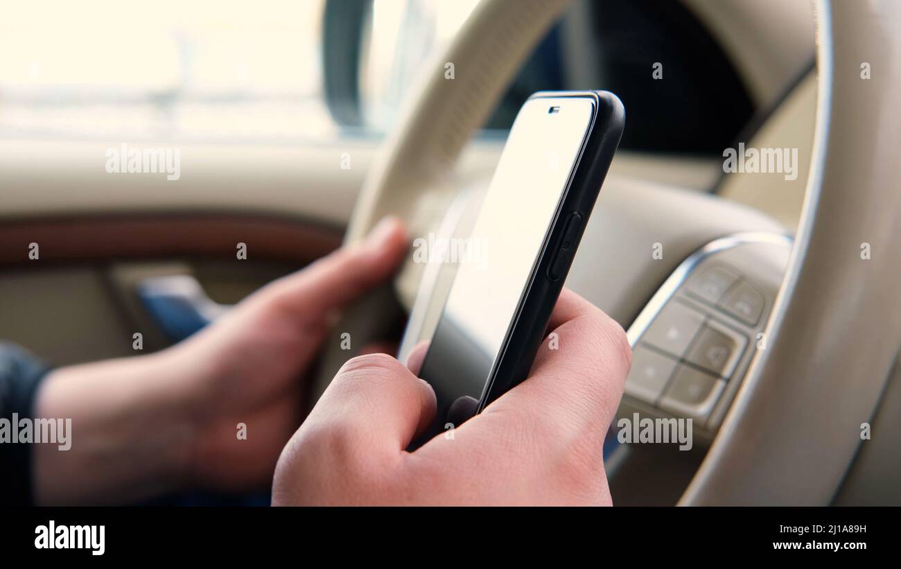 La mano di Mans tiene il telefono e tocca lo schermo in un'auto. Utilizzando il telefono e guarda il percorso sulle mappe come arrivare al luogo desiderato. Viaggi Foto Stock