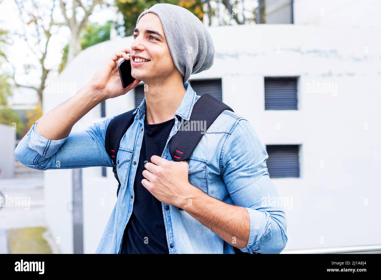 Giovane uomo moderno che usa un telefono cellulare per strada. Foto Stock