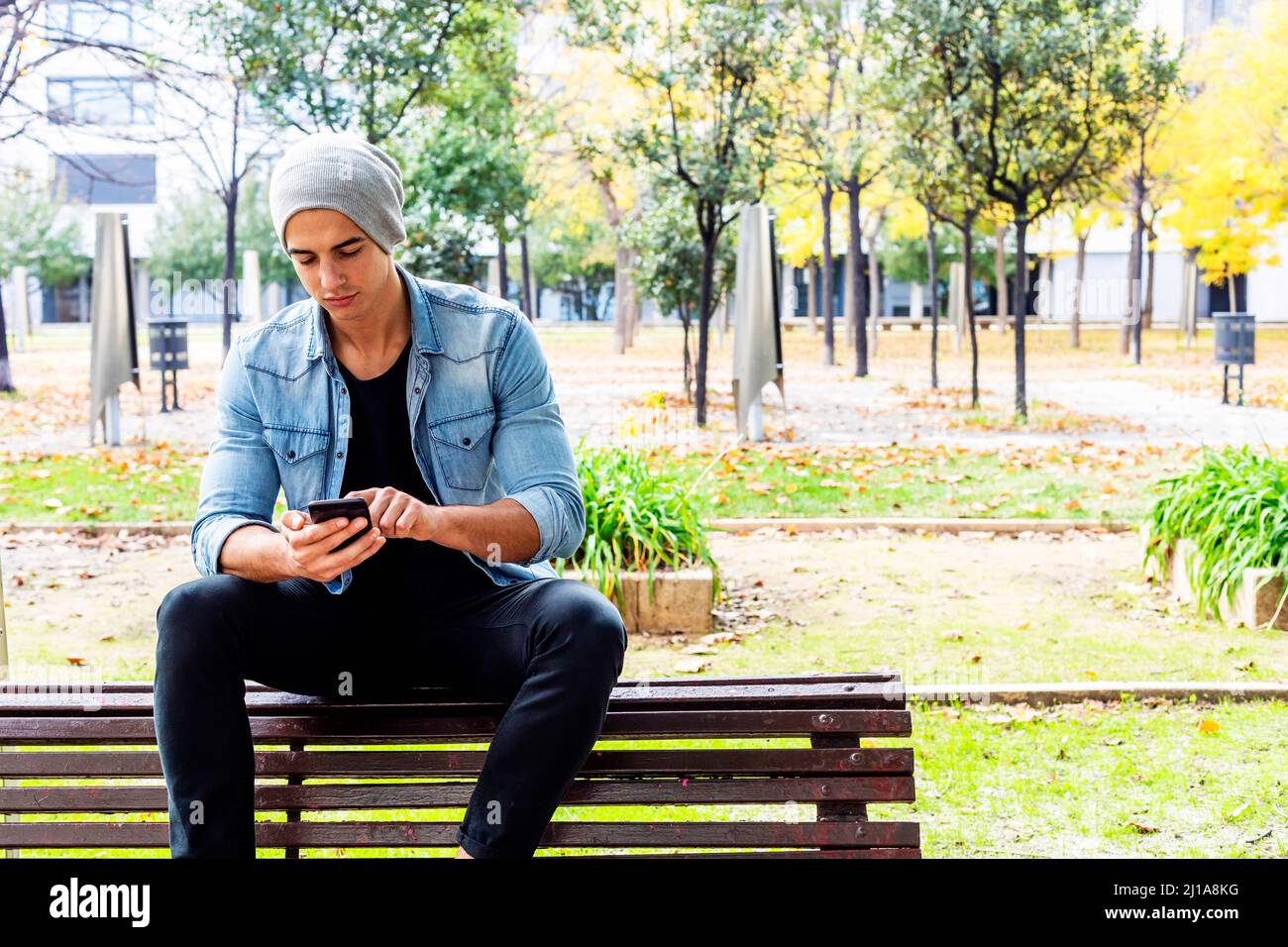 Ritratto esterno del giovane moderno con cellulare in strada. Foto Stock