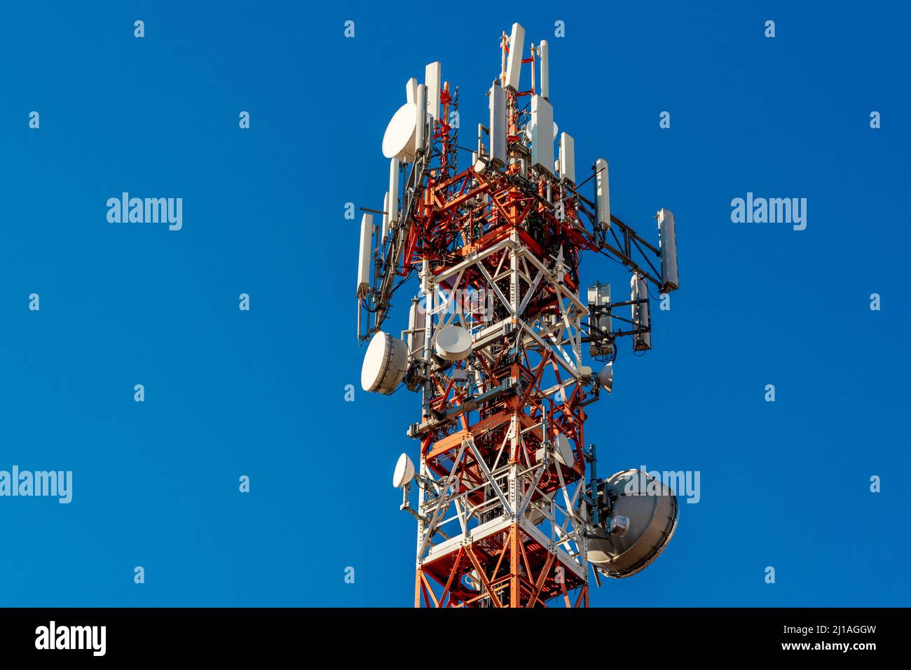 Torre metallica con antenne per telecomunicazioni e parabole colorate di rosso e bianco su blu SKY, concetto di rete 5G ad alta velocità, spazio di copia Foto Stock