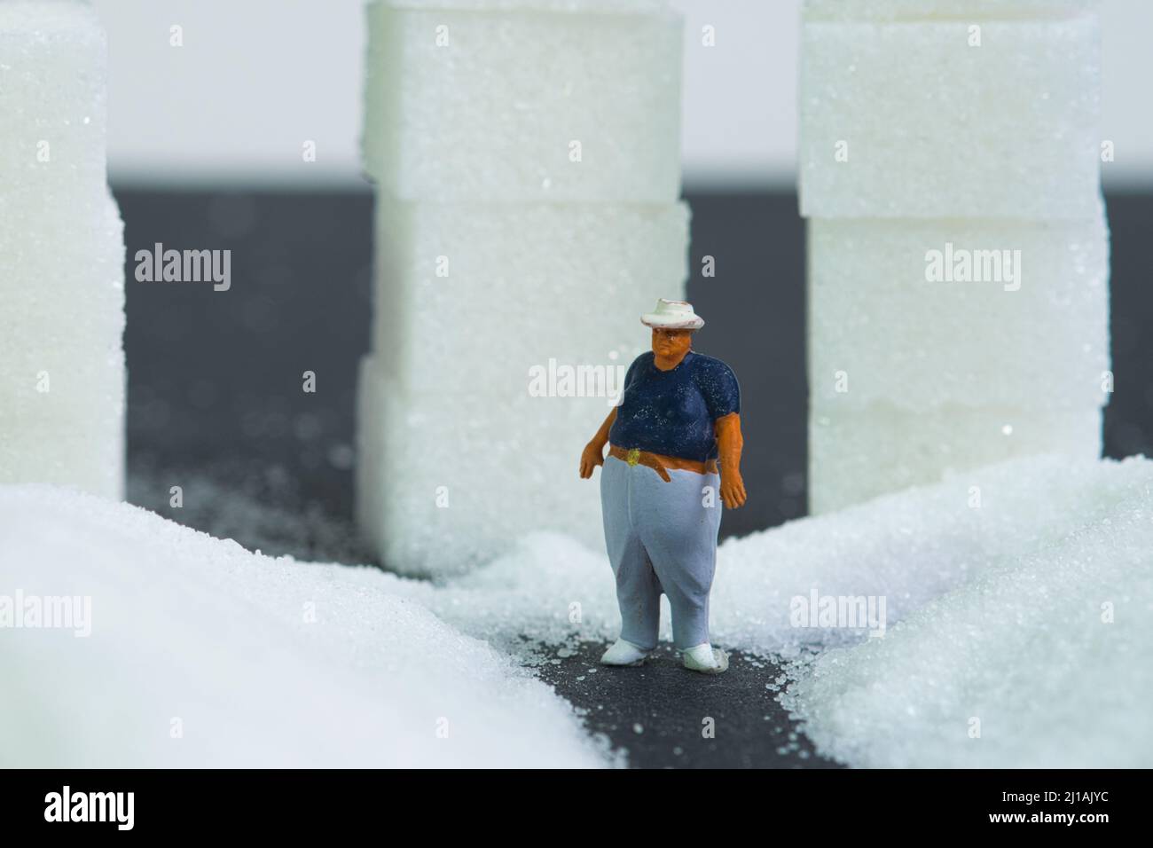 l'uomo sovrappeso si alza davanti a mucchi di cubetti di zucchero, primo piano. Concetto: Disciplina dell'equilibrio calorico Foto Stock