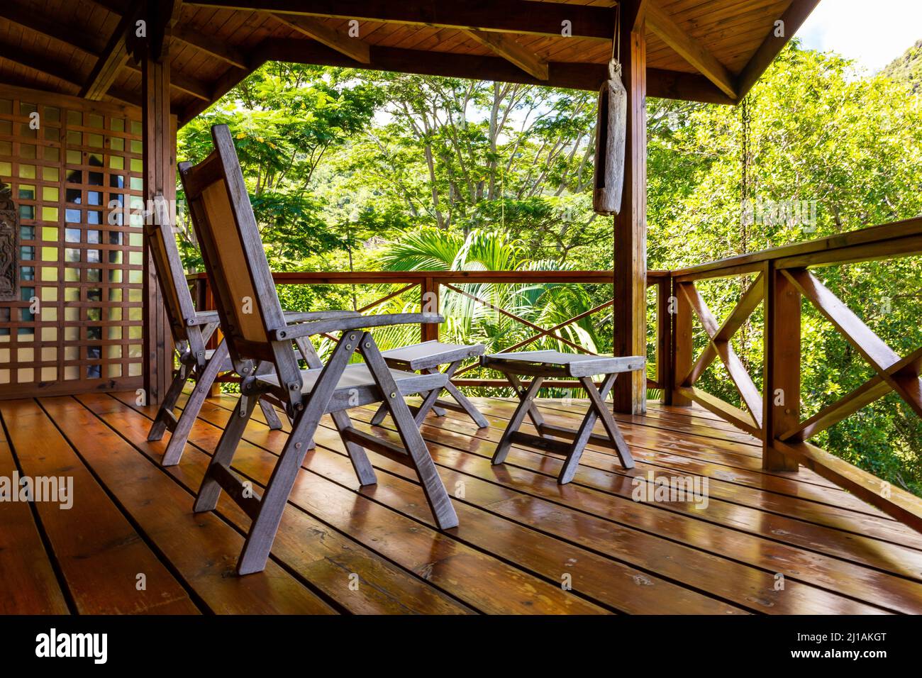 Due sedie di legno su una terrazza di legno sulle cime degli alberi della foresta pluviale del Parco Nazionale delle Seychelles con lussureggiante vegetazione tropicale e palme. Foto Stock