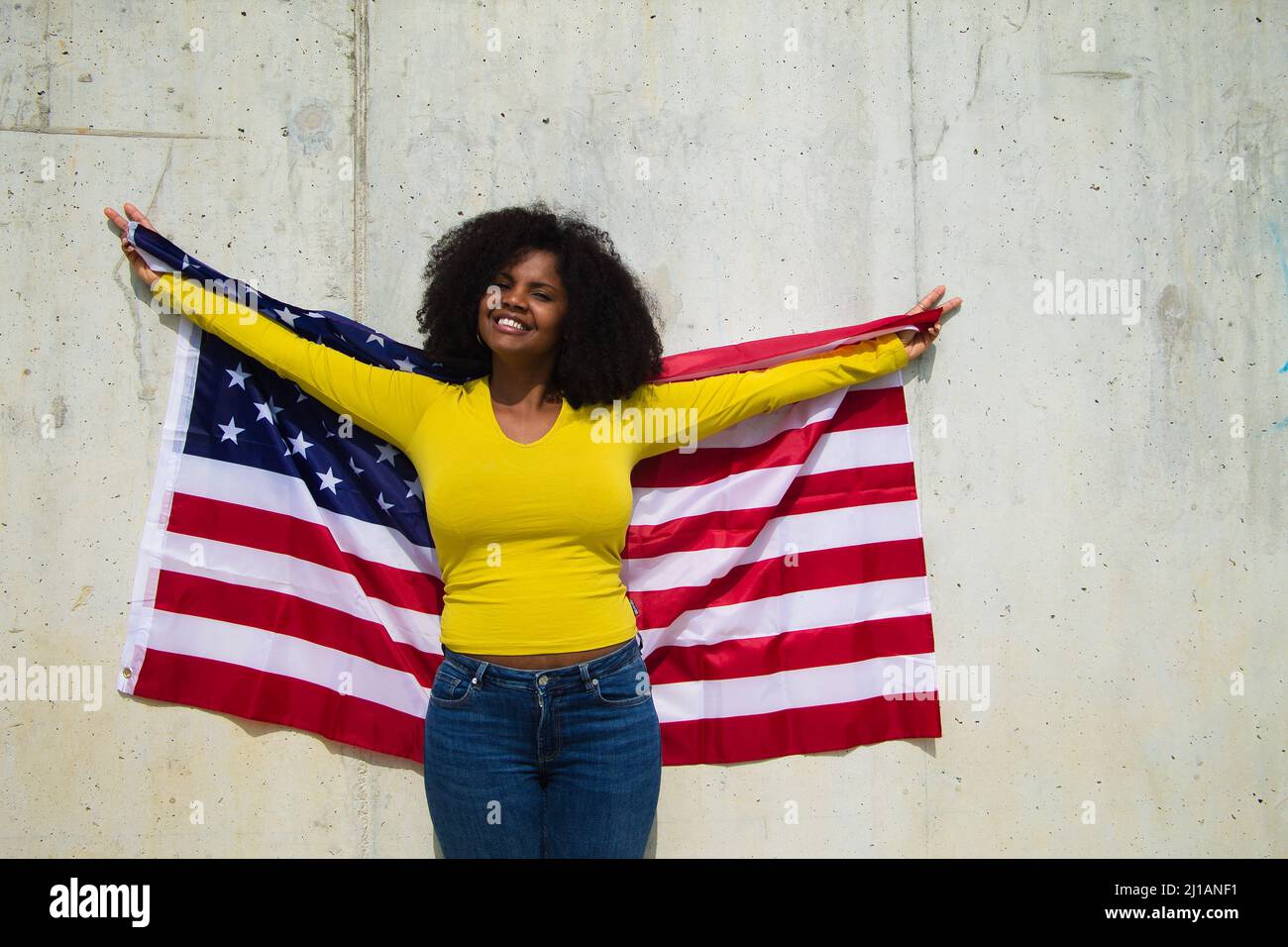 Una donna afroamericana che tiene la bandiera degli stati uniti sulle sue mani e fa cantare la vittoria con le dita Foto Stock