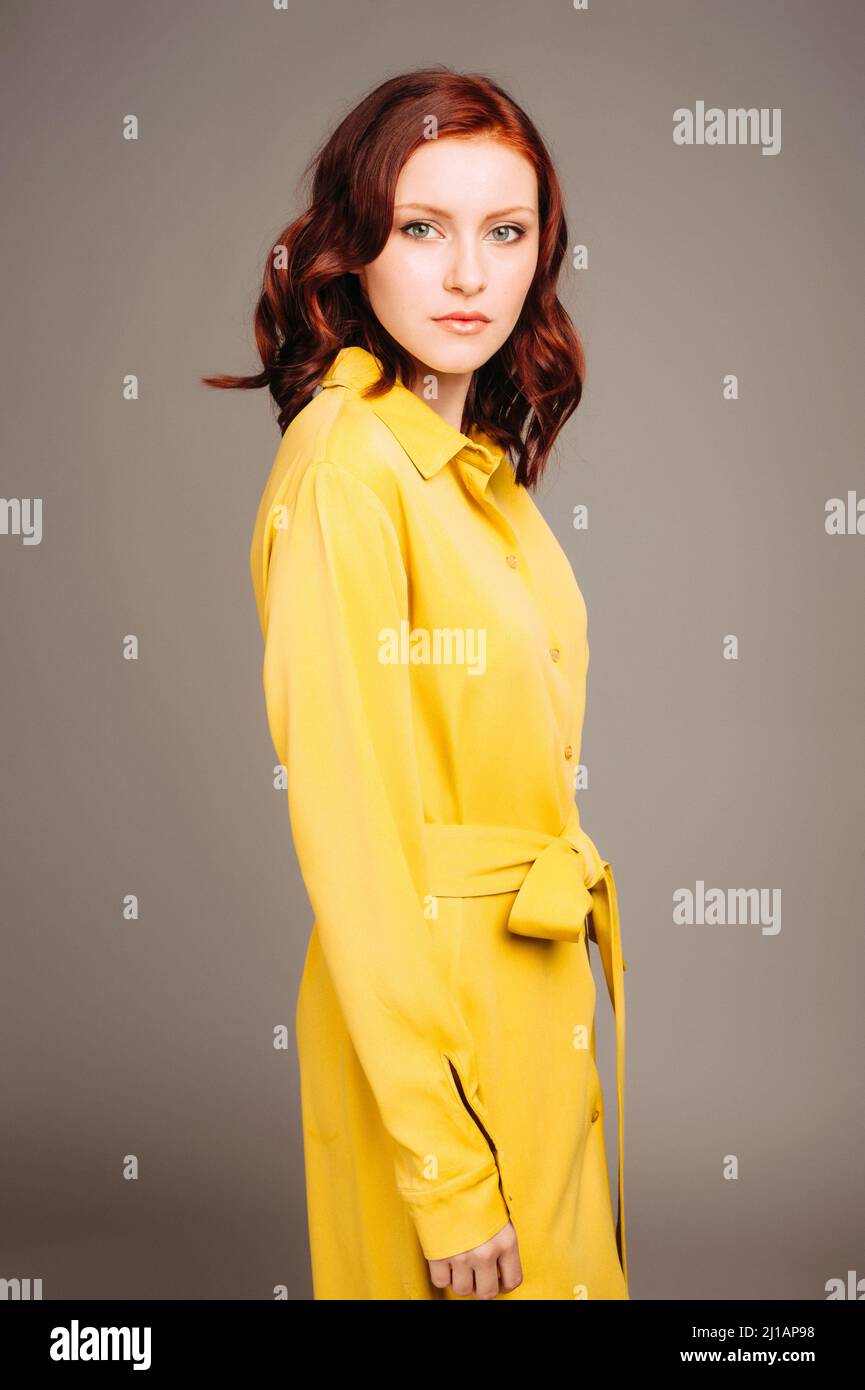 Giovane donna zenzero in abito giallo. Look femminile luminoso, stile casual al limone. Ritratto di moda su sfondo neutro studio. Foto Stock