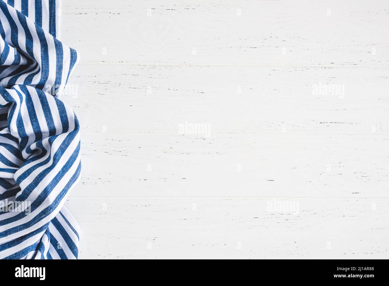 Sfondo bianco in legno con tessuto da cucina a strisce blu. Sfondo alimentare per banner web, ricette alimentari, pubblicità ed elementi di design Foto Stock