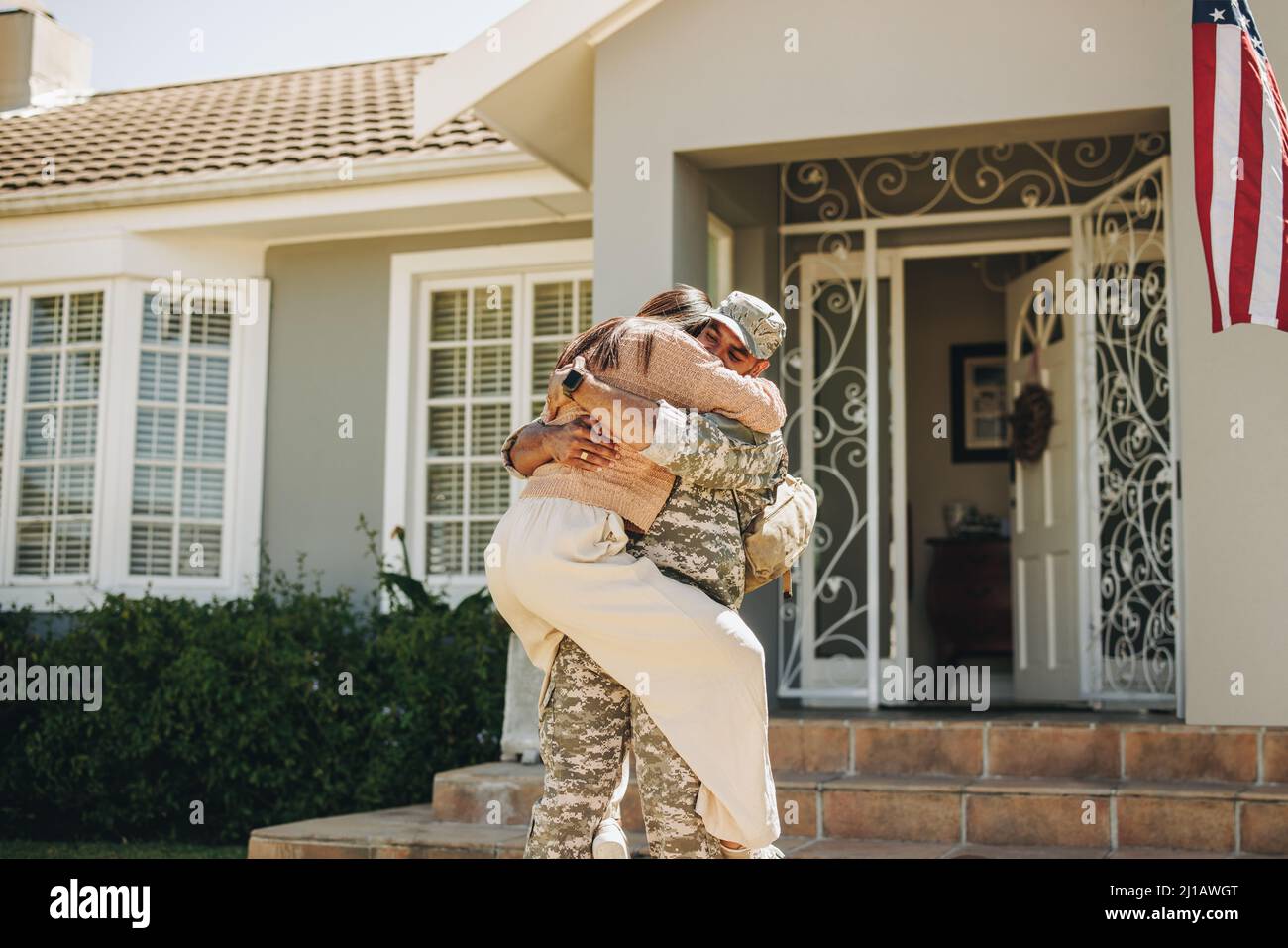 Felice giovane soldato che abbraccia sua moglie dopo essere tornato a casa dall'esercito. Giovane servitù patriottico che si riuniva con sua moglie dopo aver servito il suo contr Foto Stock