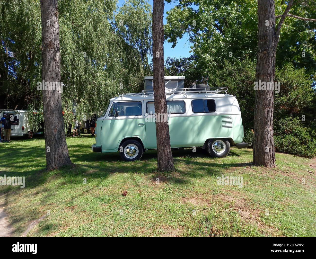 Vecchio pulmino bianco Volkswagen tipo 2 T2 Camper Kombi parcheggiato sull'erba dietro gli alberi. Mostra auto classica Suda VW. CopySpace Foto Stock