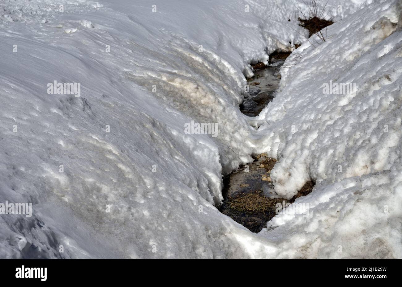 Le abbondanti nevicate hanno quasi completamente coperto il torrente le cui acque ora difficilmente si diranno verso la valle Foto Stock