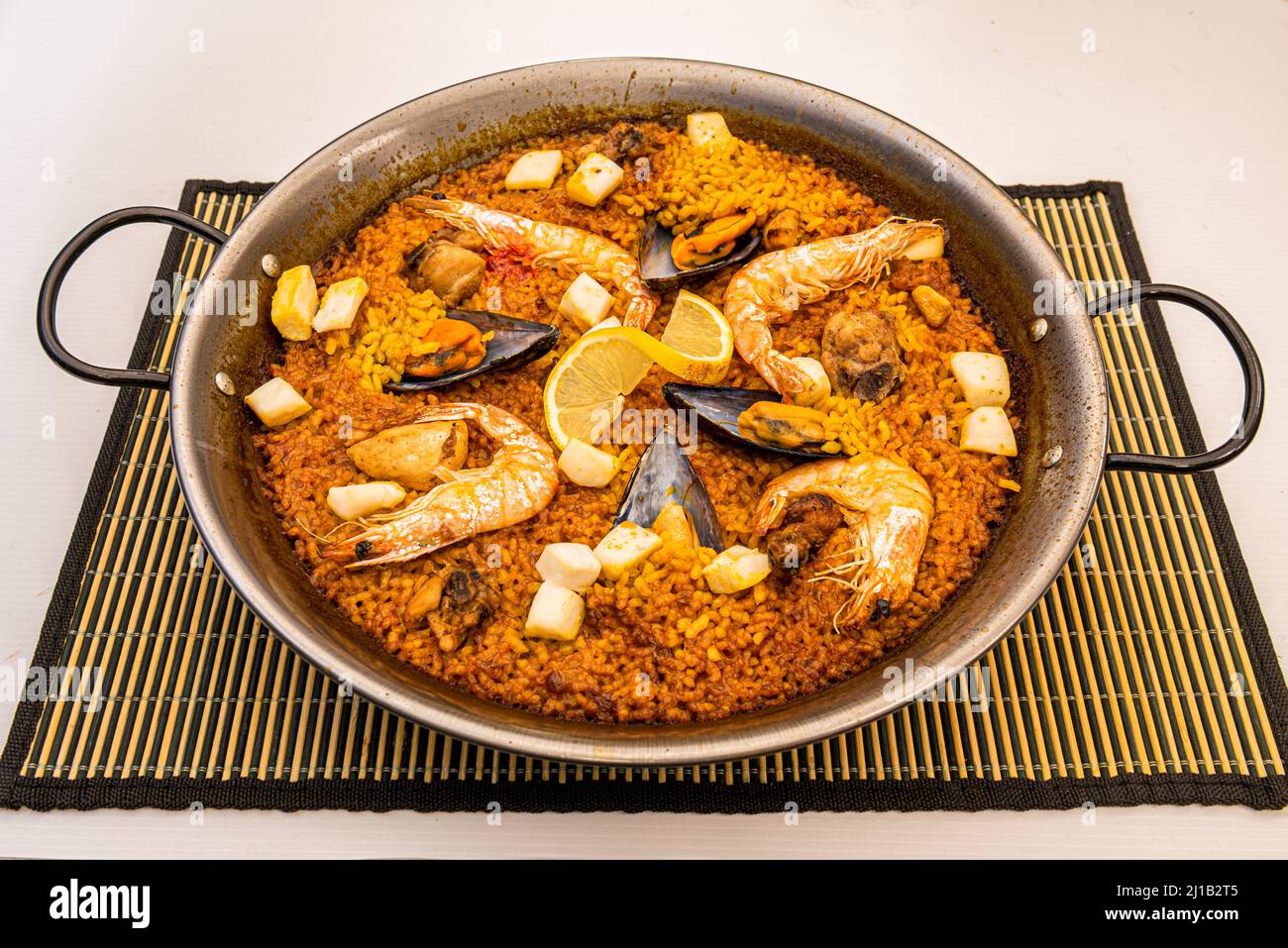 Paella valenciana di pesce con riso dorato in padella Foto Stock