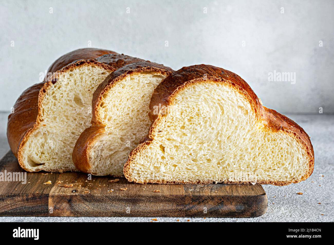 Challah o Hala è un tradizionale dolce ebraico fresco di sabato pane intrecciato (pane di pane), panna fresca (fetta di cibo) sul tagliere. Brioche per colazione ta Foto Stock