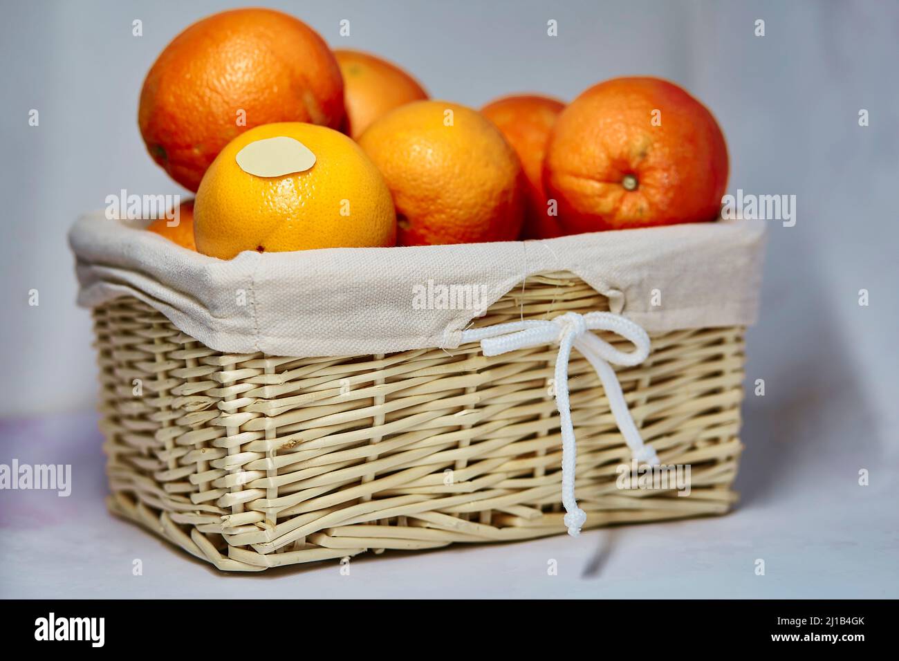 Mock up etichetta sulle arance. Cestino di vimini con arance e adesivo prodotto su di esso per il testo o il prezzo. Prodotti agricoli biologici dal mercato locale Foto Stock