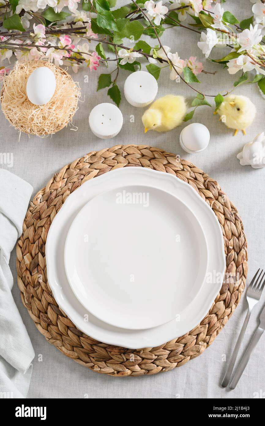 Tavola di Pasqua con pulcino giallo, uova biologiche, fiori freschi su tovaglia di lino. Vista dall'alto. Tradizione cristiana. Foto Stock