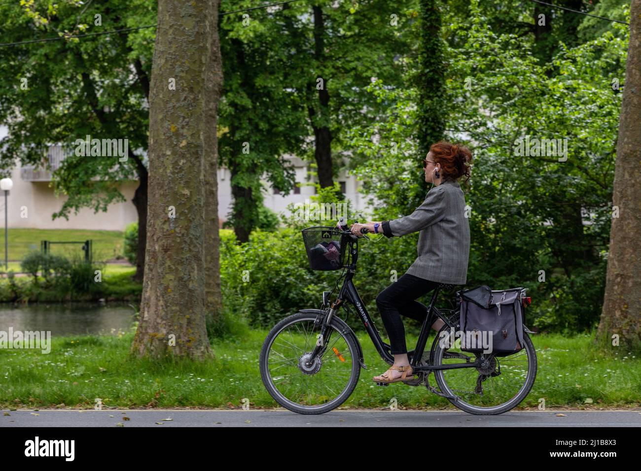 DONNA CHE GUIDA UNA BICICLETTA LUNGO LE RIVE DEL ORNE, LA PRAIRIE, CAEN, CALVADOS, NORMANDIA, FRANCIA Foto Stock