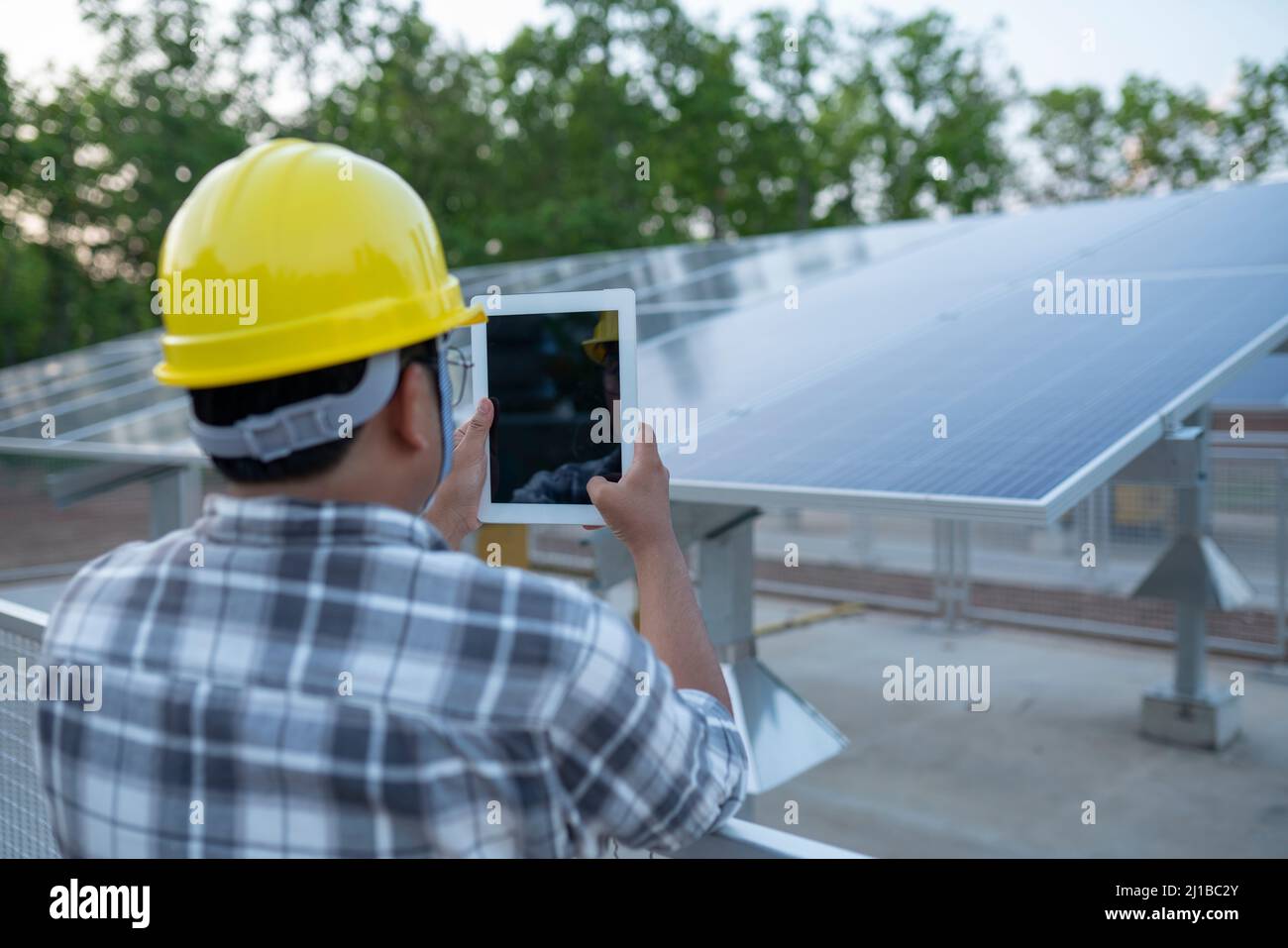 I giovani tecnici utilizzano i tablet per controllare le centrali elettriche a pannelli solari nei terreni agricoli Foto Stock