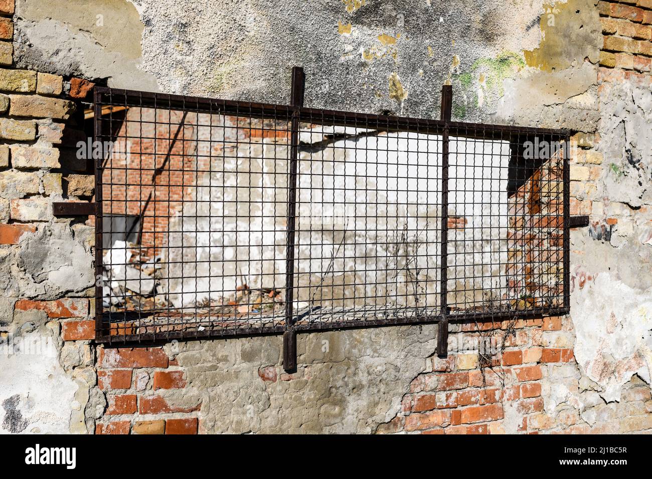 Vecchio edificio industriale rovinato con muri in mattoni danneggiati, facciata dell'edificio usurata Foto Stock
