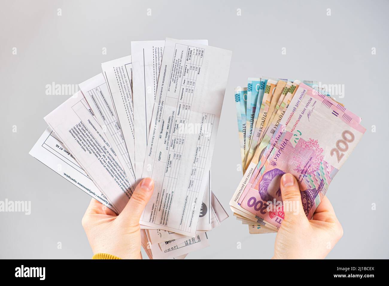Le banconote di hryvnia e i pagamenti per i servizi pubblici sono nelle mani di una persona. Pagamento per gas, elettricità e acqua in Ucraina. Marzo 21, 2022 Foto Stock