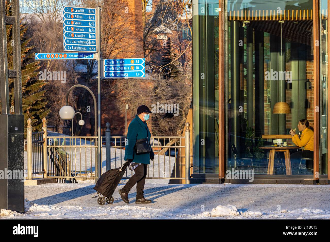STREET SCENE IN INVERNO NELLA NEVE, DONNA CON UNO SHOPPING TROLLY E COLAZIONE, TAMPERE, FINLANDIA, EUROPA Foto Stock