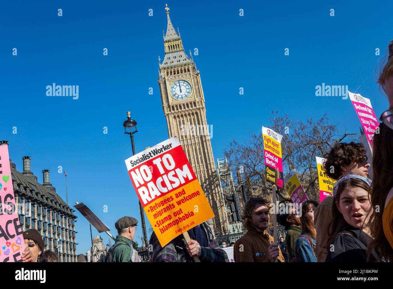 Protesta che si svolge a Londra in occasione della Giornata ONU contro il razzismo organizzata da Stand up to Racism, passando per la torre restaurata del Parlamento. Cartello di no al razzismo Foto Stock