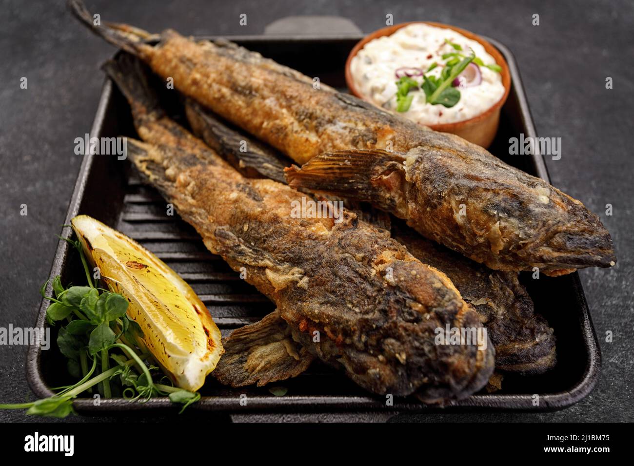 Pesce fritto Gby del Mar Nero, con limone ed erbe, su sfondo scuro Foto Stock