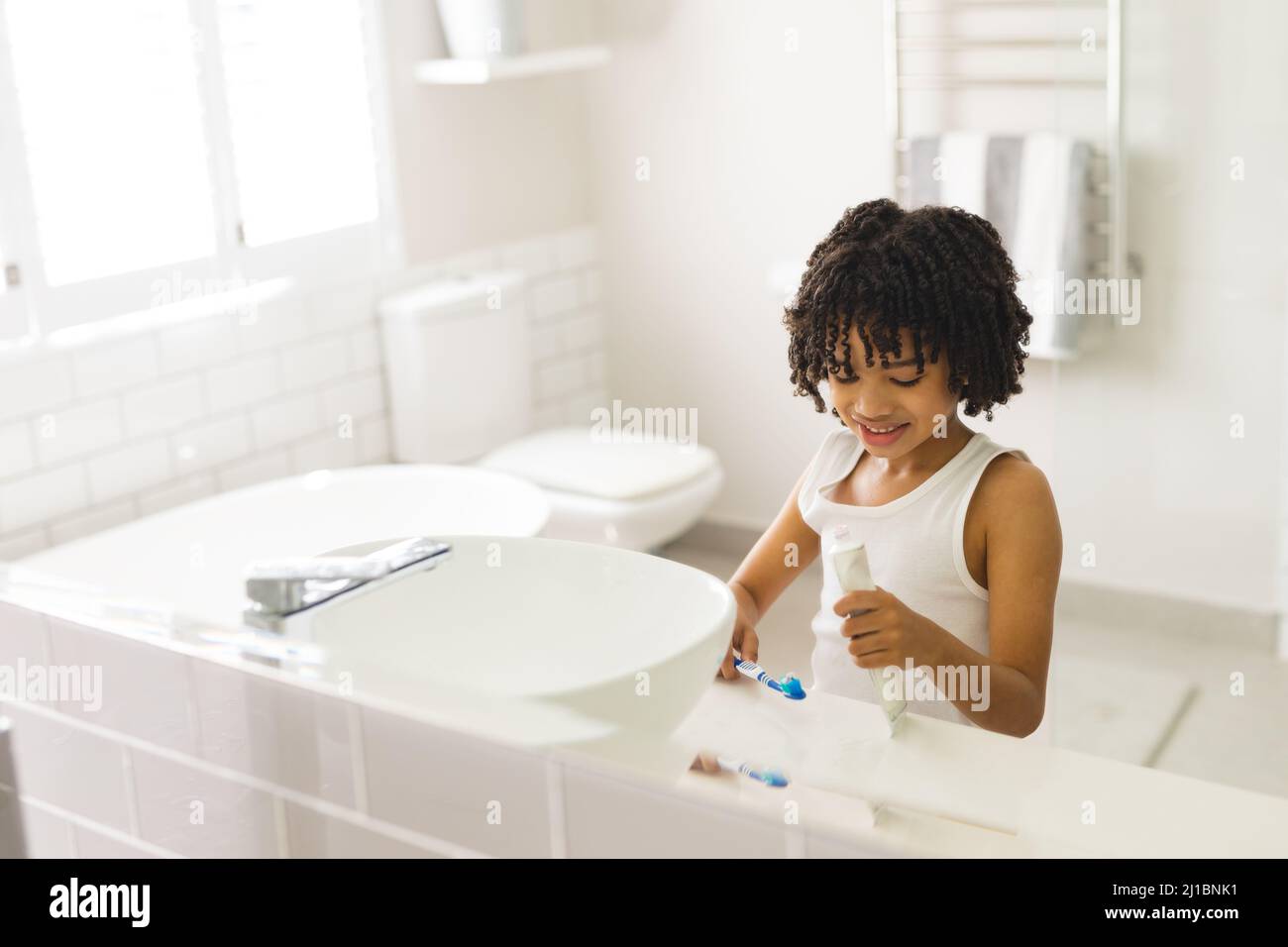 Sorridente ragazzo ispanico carino spazzolando in bagno a casa Foto Stock