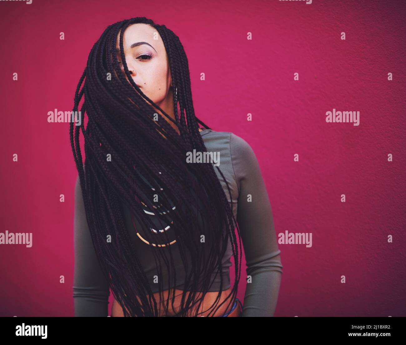 Lo stile è l'arte di essere voi stessi. Scatto di una giovane donna con trecce in posa su sfondo rosa. Foto Stock