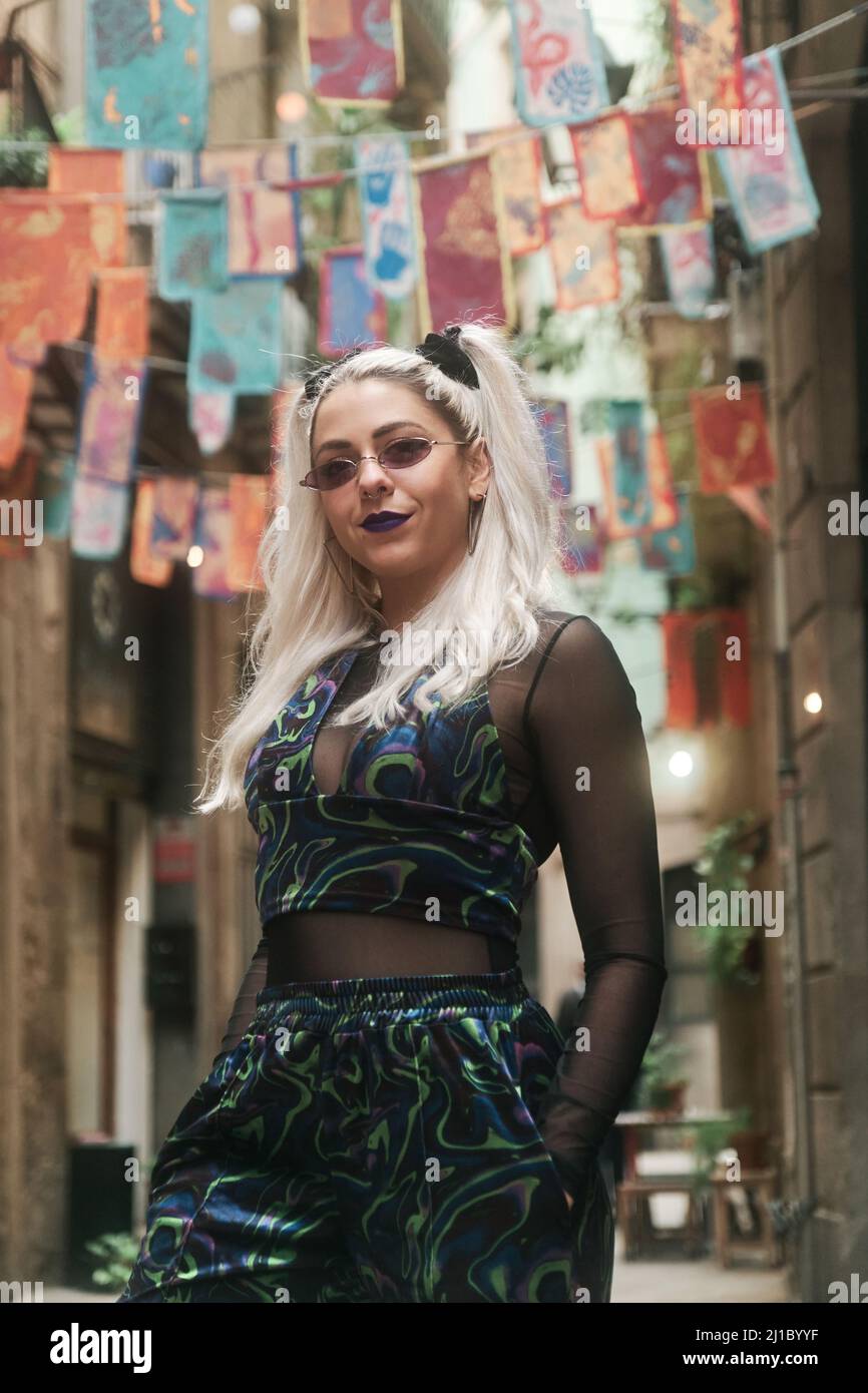 Donna alternativa sicura che guarda la fotocamera mentre si posa all'aperto per strada. Foto Stock