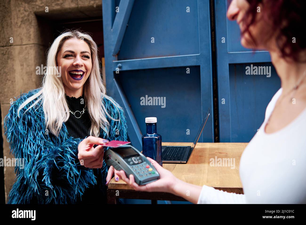 Cliente femminile che effettua un pagamento contactless con una carta di credito in un bar. Foto Stock