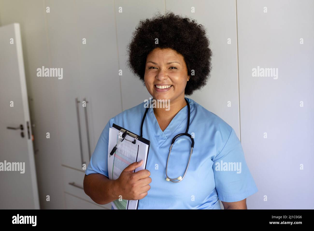 Ritratto di sorridente infermiera femminile afroamericana per adulti di media età con stetoscopio e appunti Foto Stock