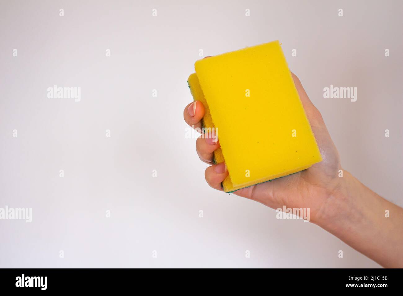 Mano che tiene una spugna gialla isolata su sfondo bianco. Foto Stock