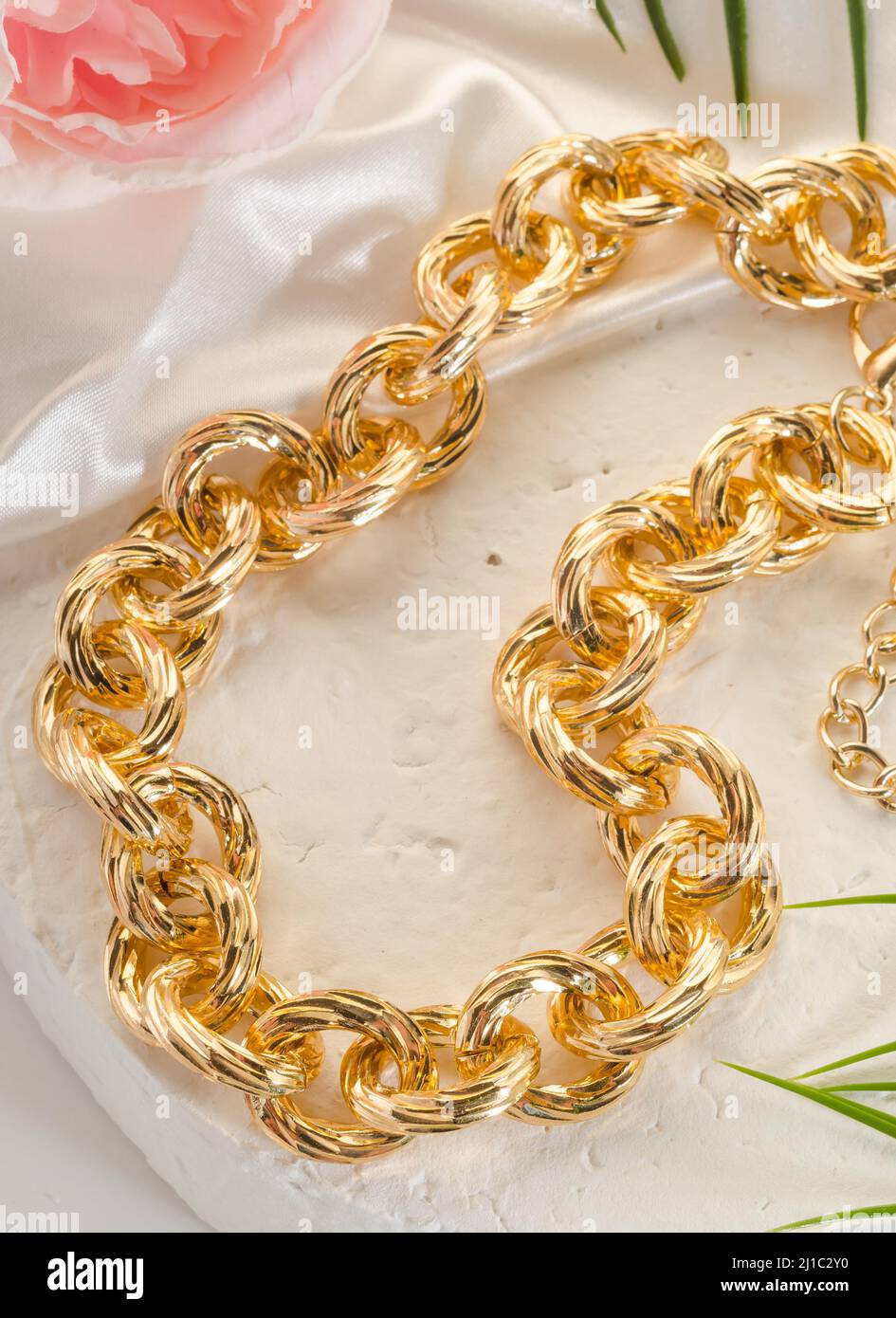 Bijouterie moda - un grande bracciale a catena in oro su un primo piano bianco Foto Stock