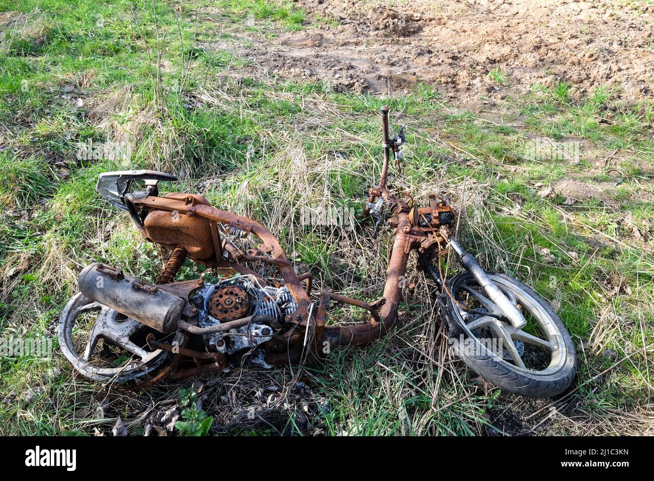 ciclomotore bruciato scaricato in un campo Foto Stock