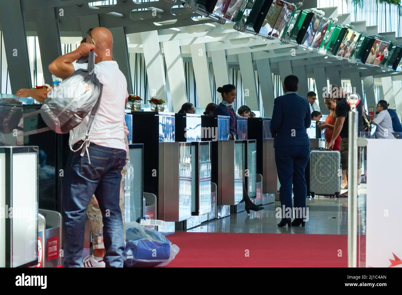 I passeggeri o le persone che effettuano il check-in per un volo dal primo piano dell'aeroporto di Mauritius in piedi ai banchi di check-in o ai banchi di concetto di viaggio aereo Foto Stock