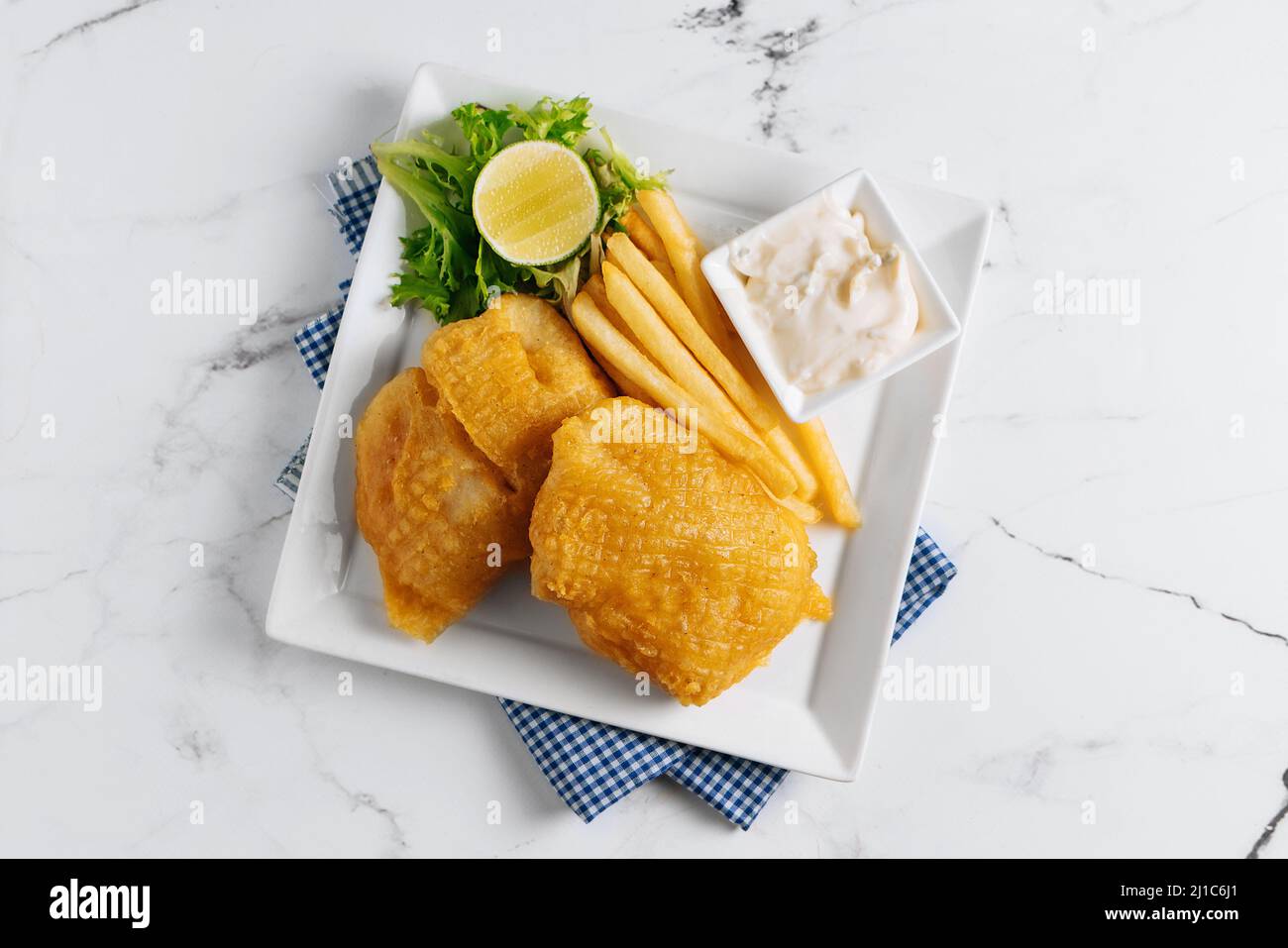 Pesce fritto e patatine fritte con lime in un cestino di piatti isolato su tovagliolo vista laterale su sfondo grigio famoso indiano e pakistano cibo Foto Stock