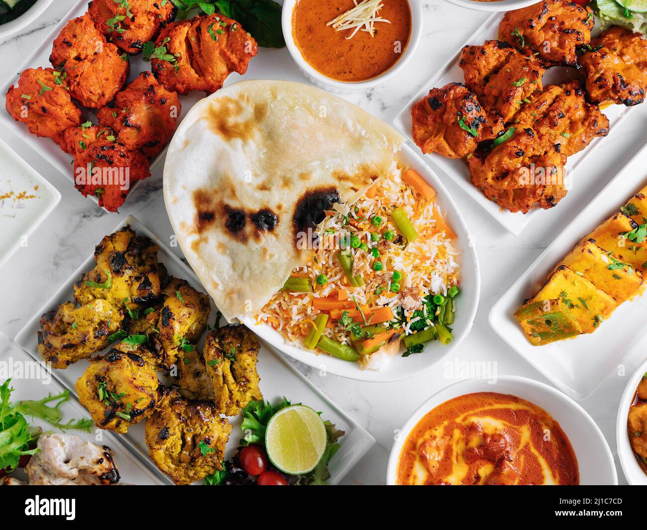 Assortiti famosi indiani e pakistani cibo da tavola verdure biryani, pollo al burro, paneer pollo Tikka boti kebab, lime, Kali Mirchi, salsa di pomodoro, r Foto Stock