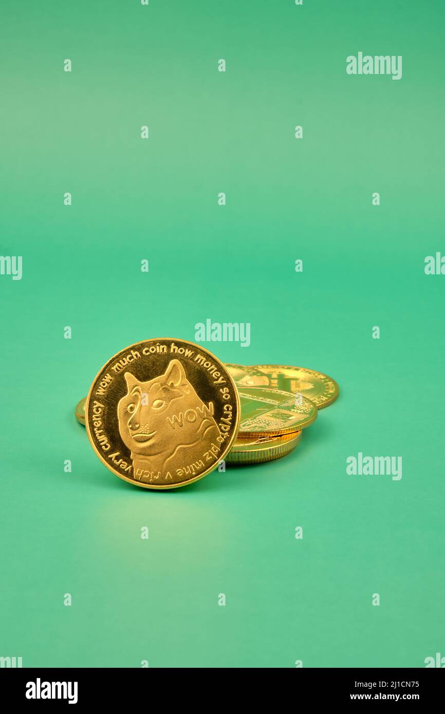 Vista verticale dei token di criptovaluta, come dogecoina, bitcoin, litecoina ed eterero con sfondo verde. Foto Stock