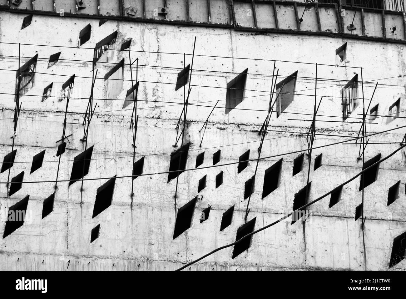 Da sotto cavi bianchi e neri e ombre di cartelli quadrati situati contro pareti di cemento intemperie sulla strada della città Foto Stock