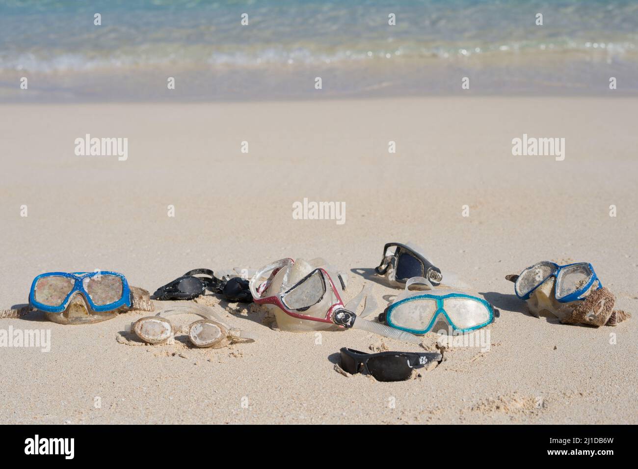 Nuota occhiali e maschere nella sabbia vicino all'acqua su una spiaggia soleggiata. Occhiali smarriti e trovati. Hawaii, Stati Uniti Foto Stock
