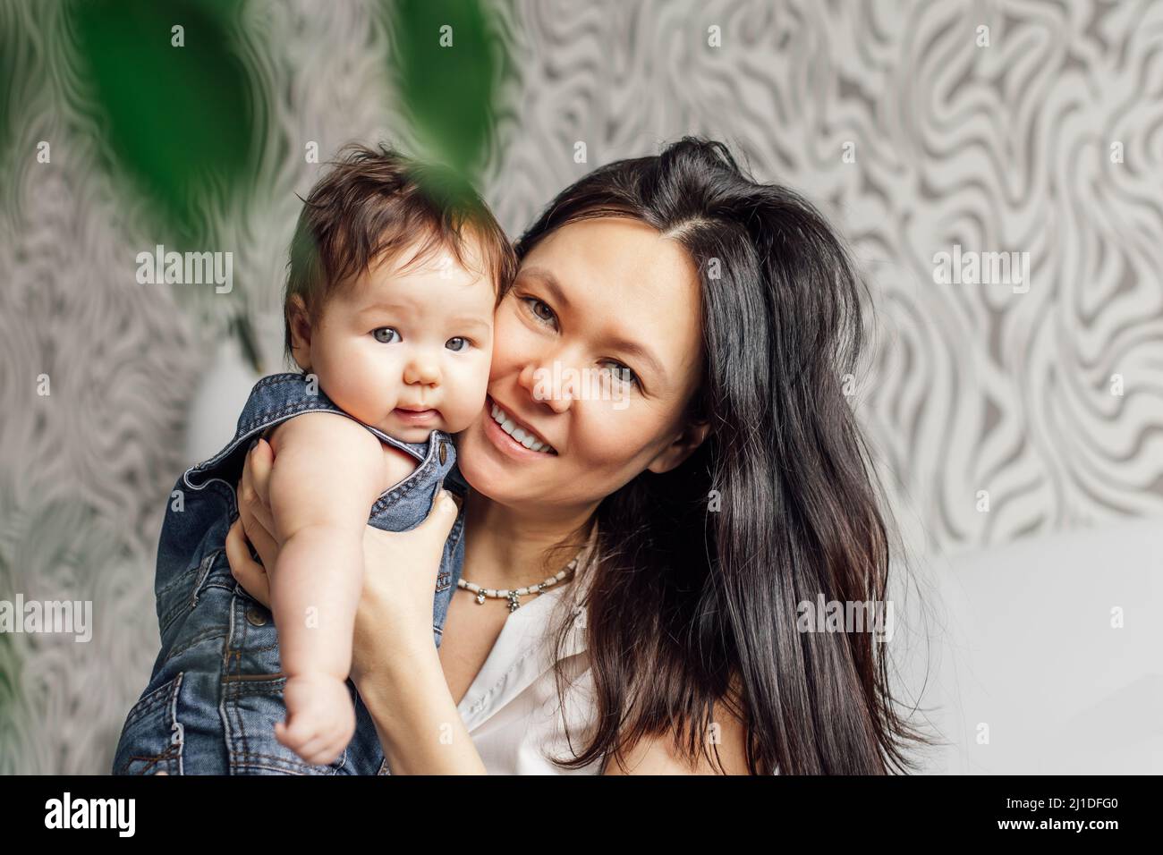 Ritratto di madre sorridente con la figlia piccola in primo piano camera da letto, spazio di copia libero, sfondo sfocato. Buon divertimento con il bambino carino, cattura felice Foto Stock