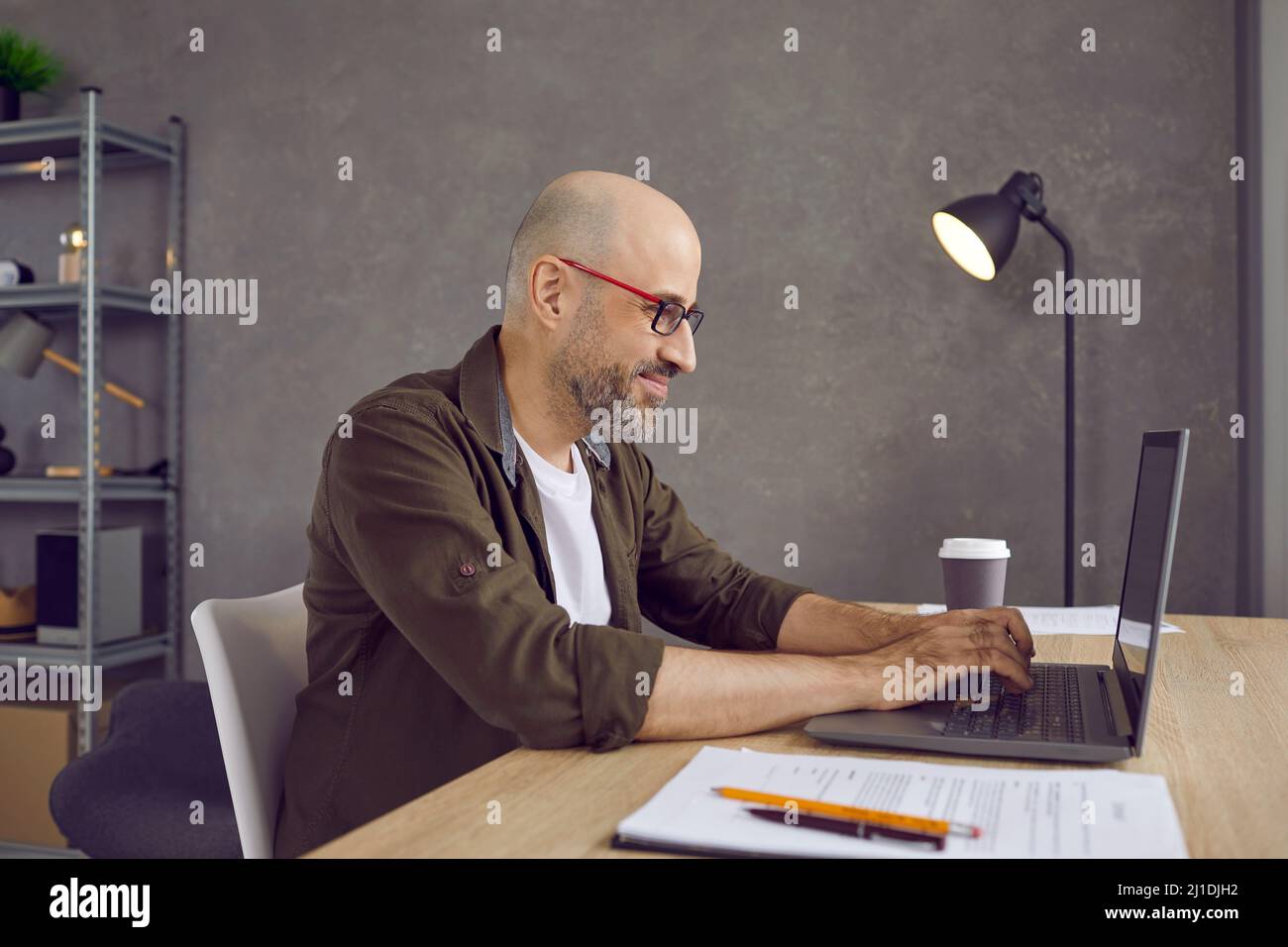 Un uomo sorridente, un freelance, lavora online su un notebook Foto Stock