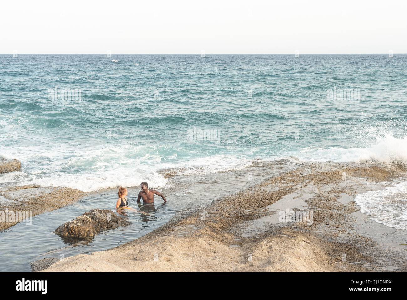 due giovani bagnano in mare, da lontano Foto Stock