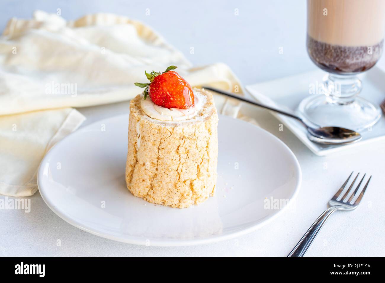 Torta di tronchi di fragola su sfondo bianco. Con cioccolata calda sul lato. Primo piano Foto Stock