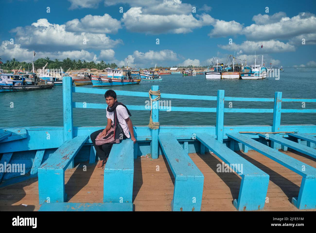 Un giovane indiano su un traghetto che passa dal Porto Vecchio di Mangalore (Mangaluru) al Bengre; barche da pesca in b/g; Mangalore, Karnataka, India Foto Stock