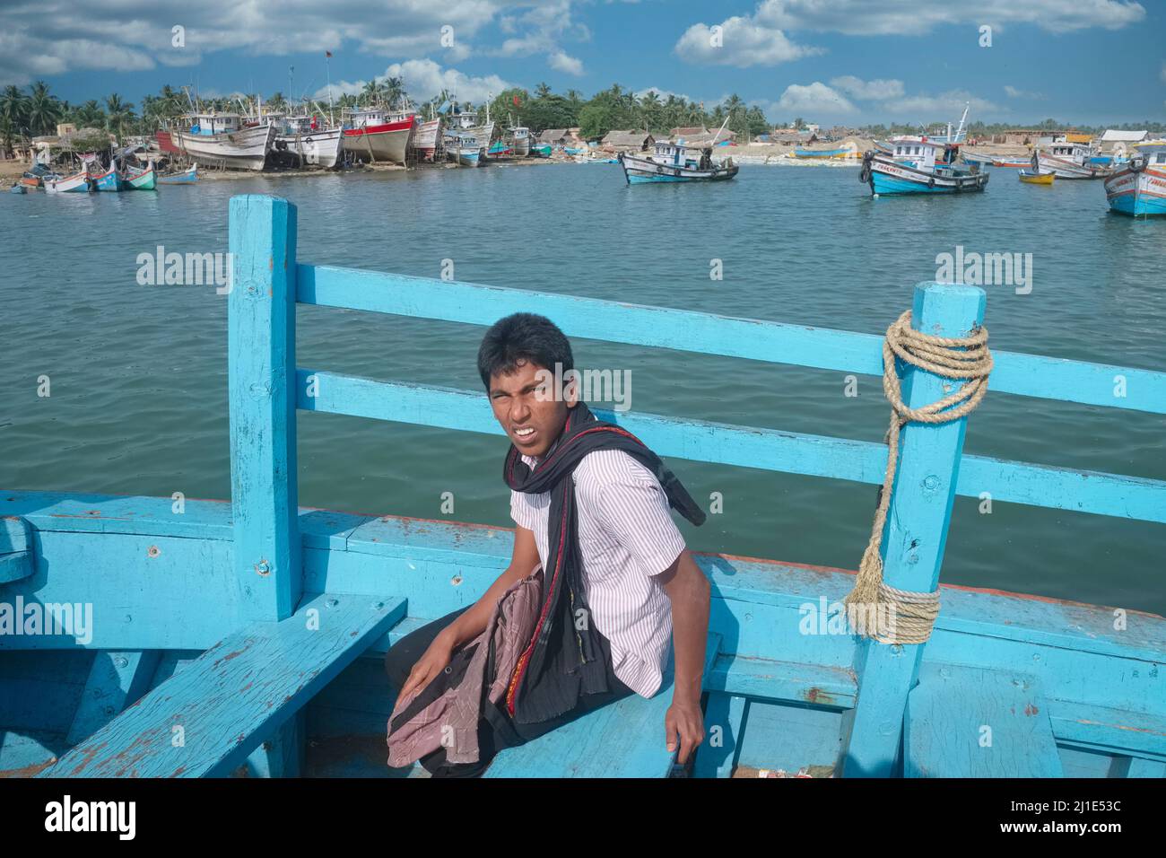 Un giovane indiano su un traghetto che passa dal Porto Vecchio di Mangalore (Mangaluru) al Bengre; barche da pesca in b/g; Mangalore, Karnataka, India Foto Stock