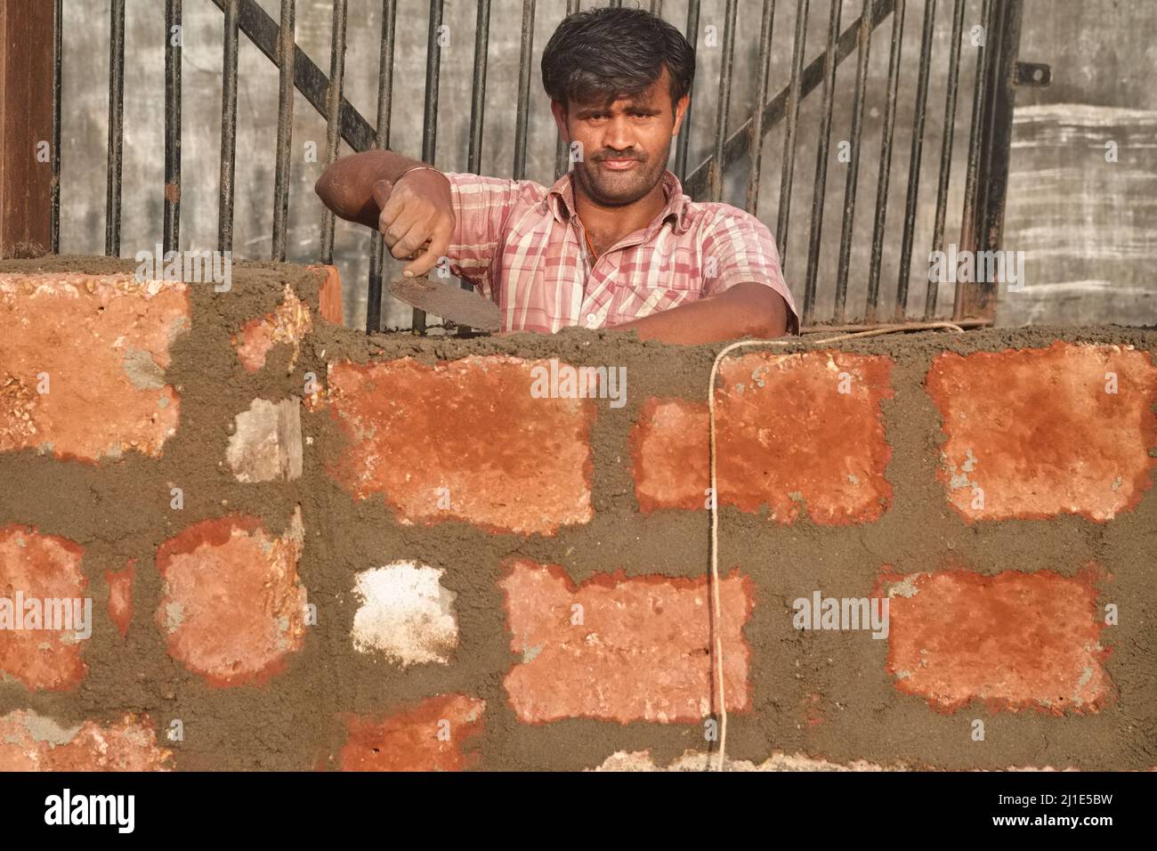 Un muratore, un salario quotidiano a Mangalore, Karnataka, India meridionale, costruendo un muro di mattoni Foto Stock