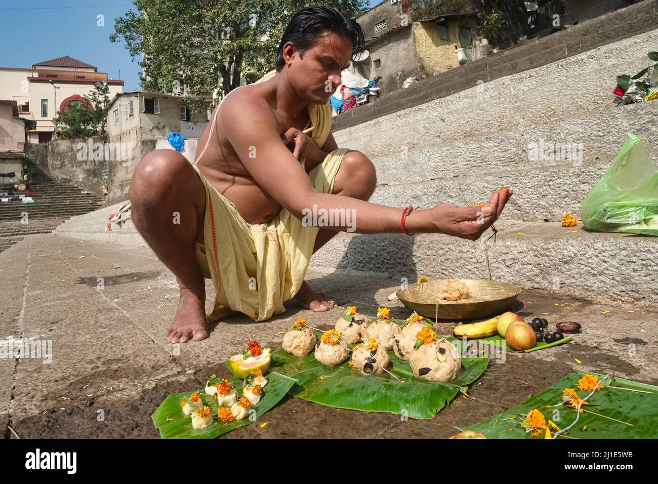 A Banganga Tank a Walkeshwar, Mumbai, India, un luogo sacro indù, un uomo esegue riti Shraddha per il suo padre defunto, offerte sulle foglie di banana Foto Stock