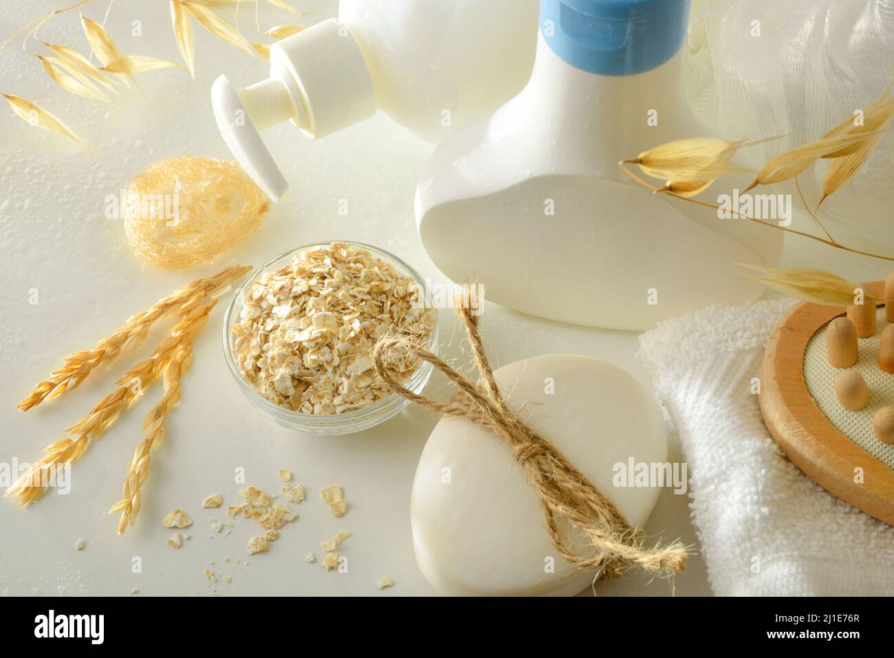 Prodotti per doccia con estratto di avena in contenitori con elementi per l'igiene personale su tavola bianca. Vista rialzata. Composizione orizzontale. Foto Stock