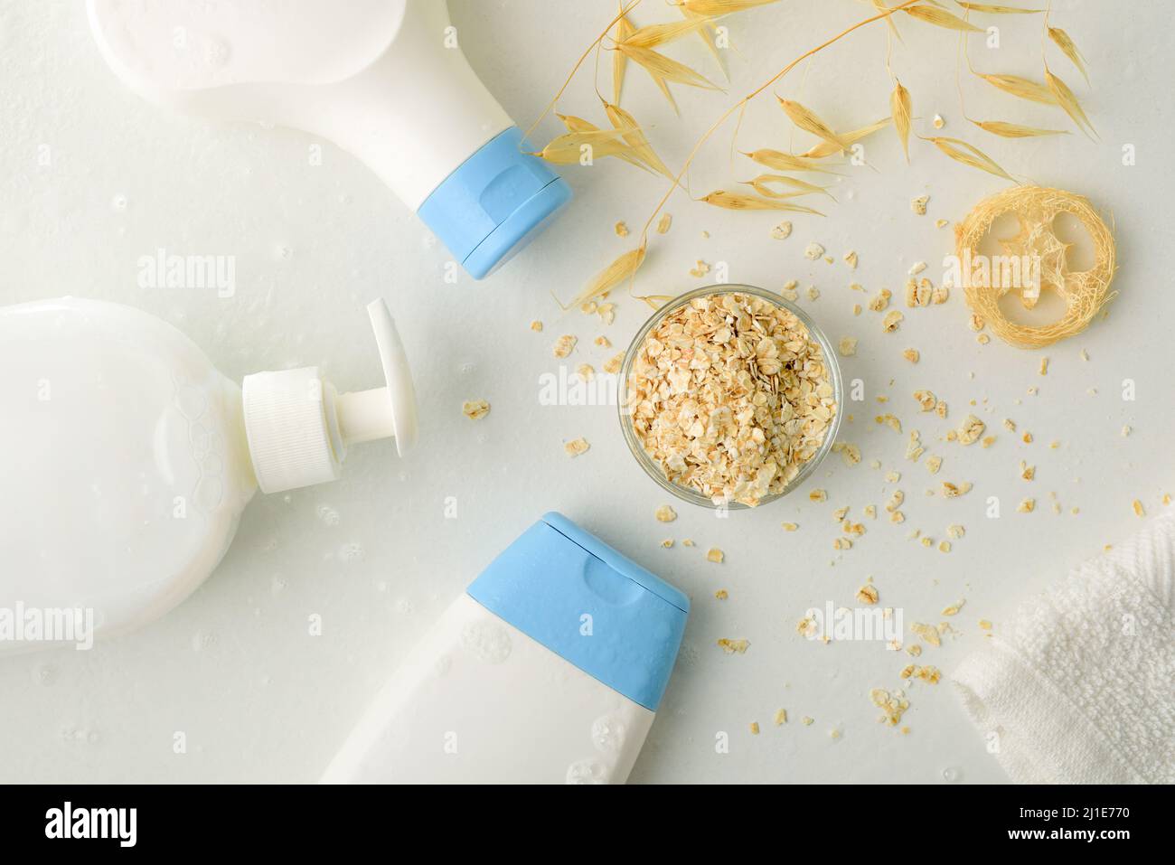 Particolare dei prodotti da bagno con estratto di avena con paillette e fiocchi su tavola bianca. Vista dall'alto. Composizione orizzontale. Foto Stock